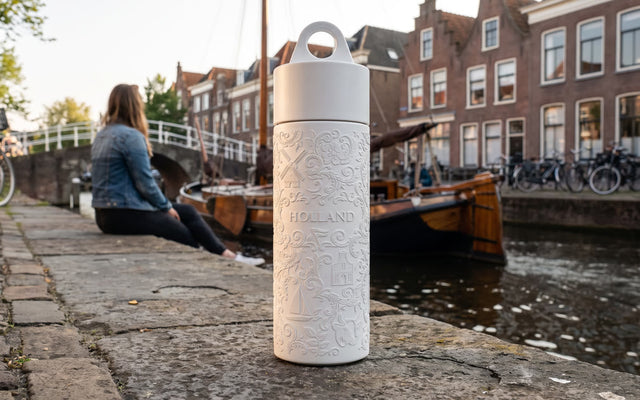 Join the Pipe Holland reusable sugarcane bottle on a canal quay in a Dutch town at golden hour