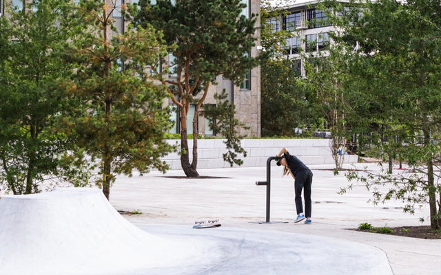 Person using public drinking water refill stations Europe in a park setting among trees.