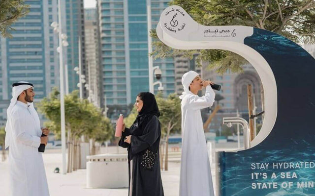 People engaging with the Dubai Can initiative water station outdoors, promoting hydration and sustainability.