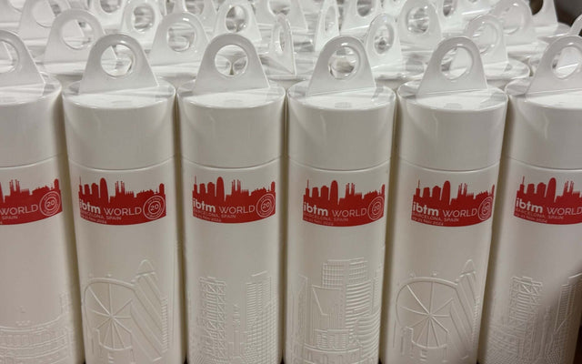 Reusable water bottles IBTM anniversary displayed in rows with city skyline design on the side.