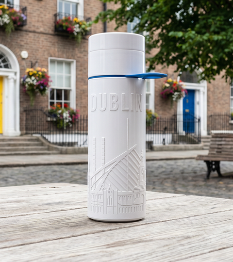 Dublin City Bottle 0.5L reusable sugarcane water bottle on a table in front of colourful Dublin doors