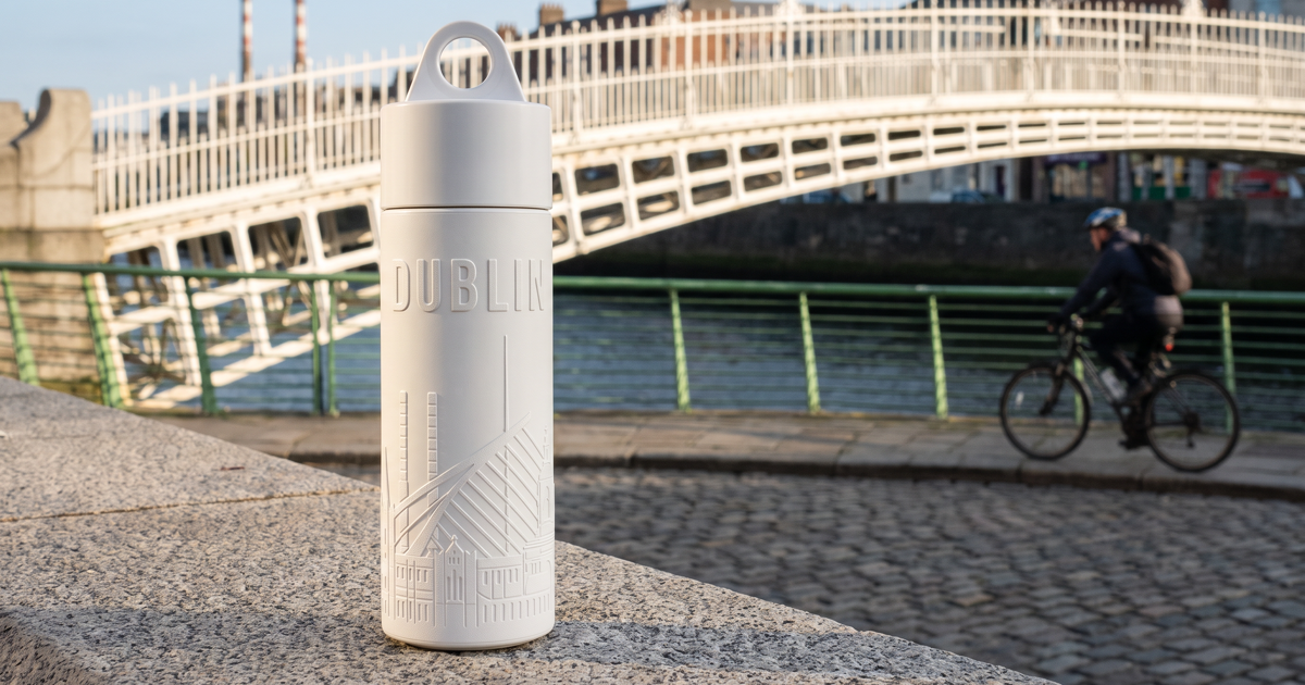 Reusable Dublin water bottle on the Liffey boardwalk with the Ha'penny Bridge behind it
