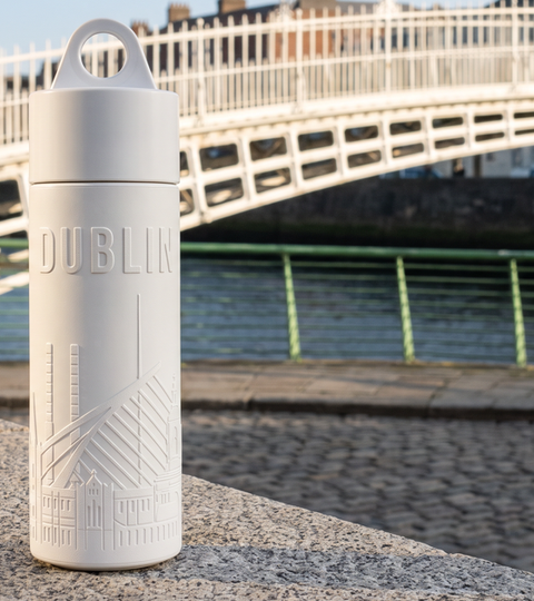Reusable Dublin water bottle on the Liffey boardwalk with the Ha'penny Bridge behind it