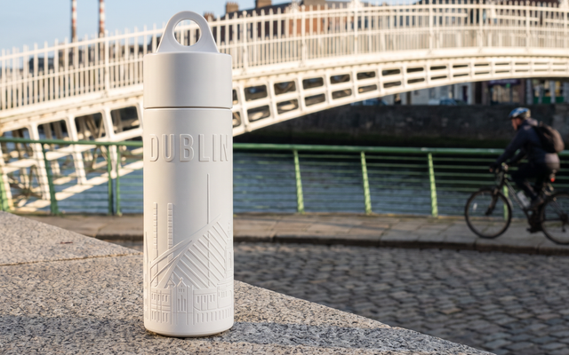 Reusable Dublin water bottle on the Liffey boardwalk with the Ha'penny Bridge behind it
