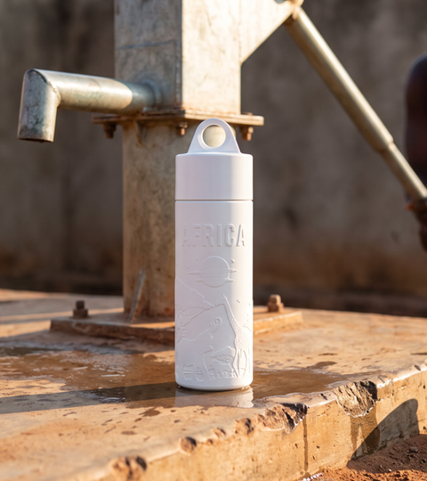 Join the Pipe Africa reusable sugarcane water bottle at a hand-pump well, woman pumping water in the background